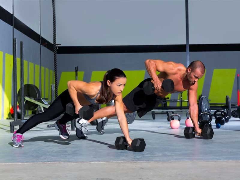 Professional trainer supporting a gym member